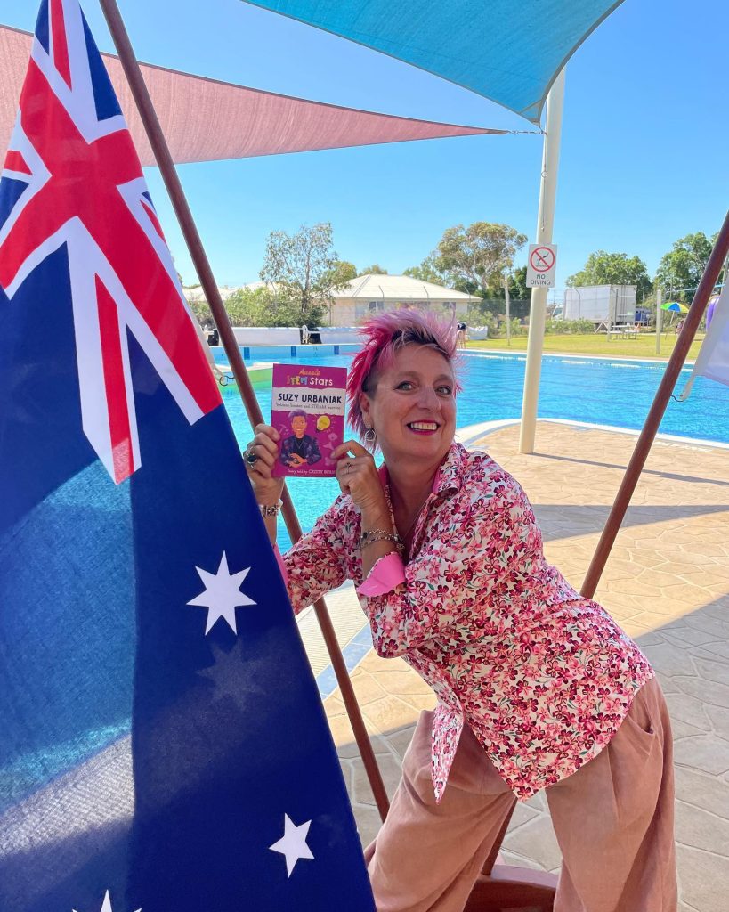 Woman smiling with book next to Australian flag