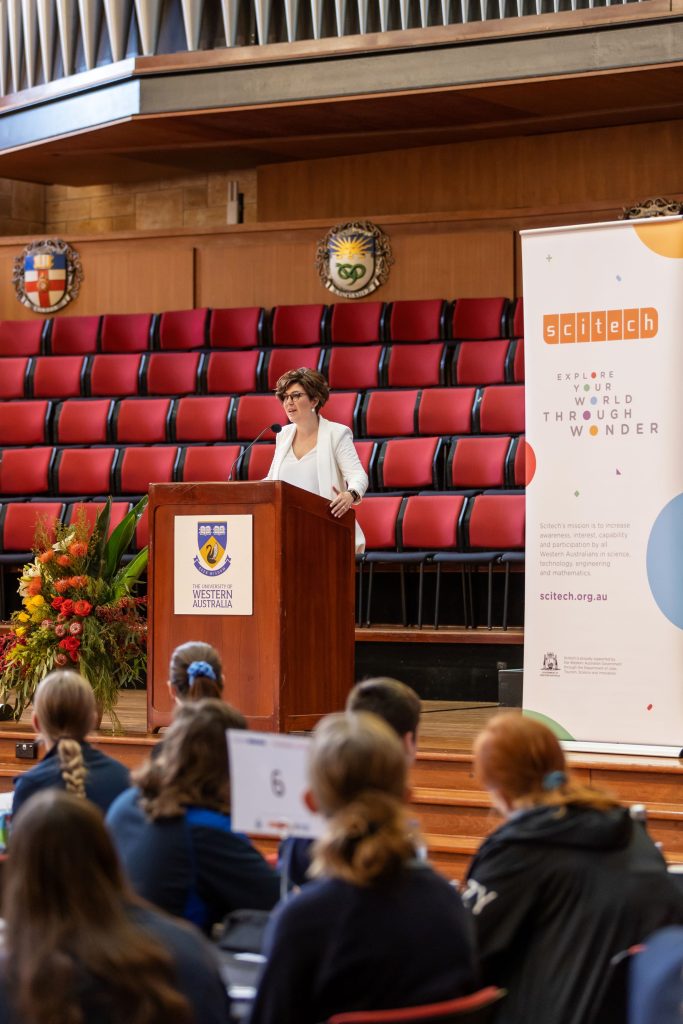 woman on stage speaking to students