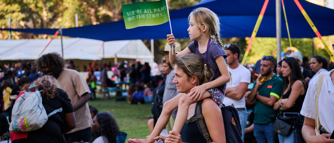child sitting on woman's shoulders at community event