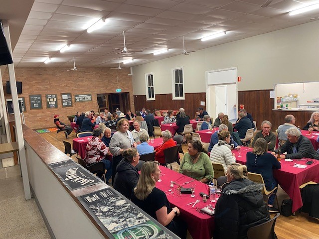 people sitting at tables in community hall