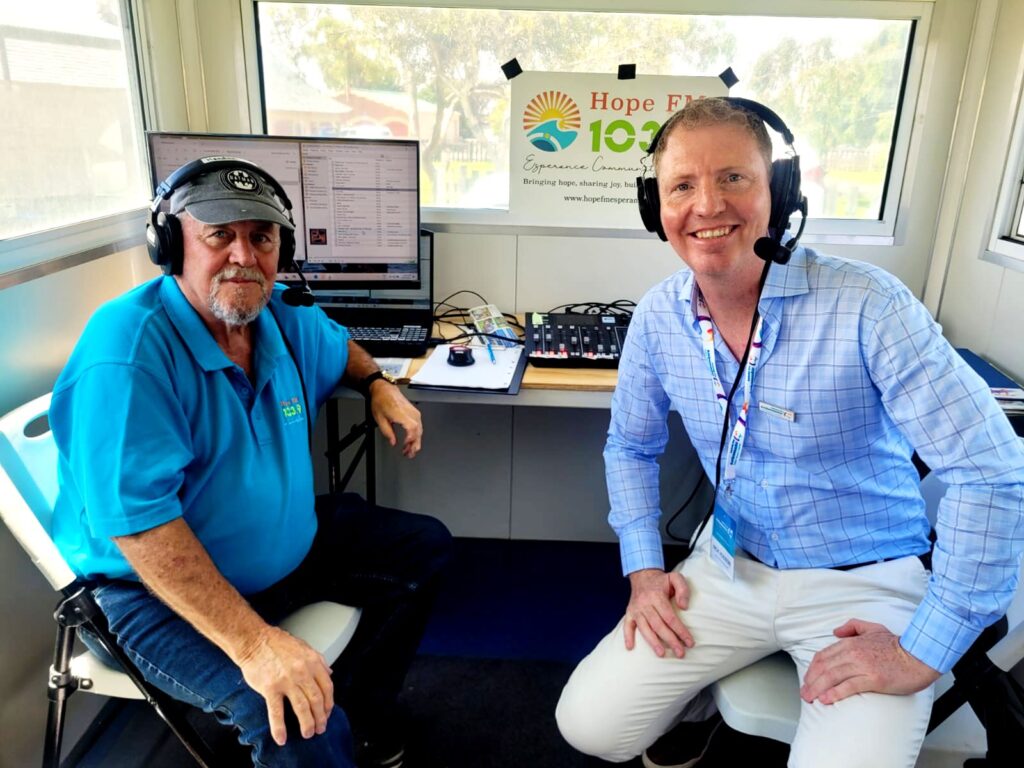 two men sitting wearing headphones for radio broadcast