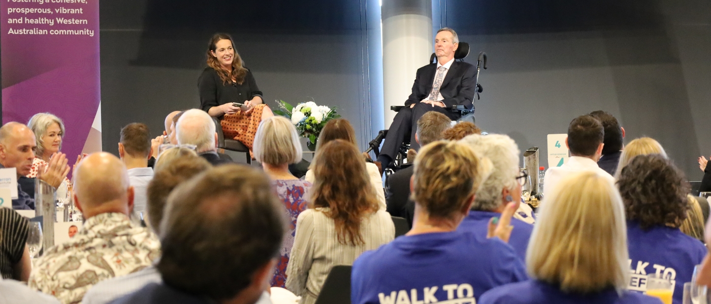 neale daniher ao and bec daniher sitting on stage with audience looking on