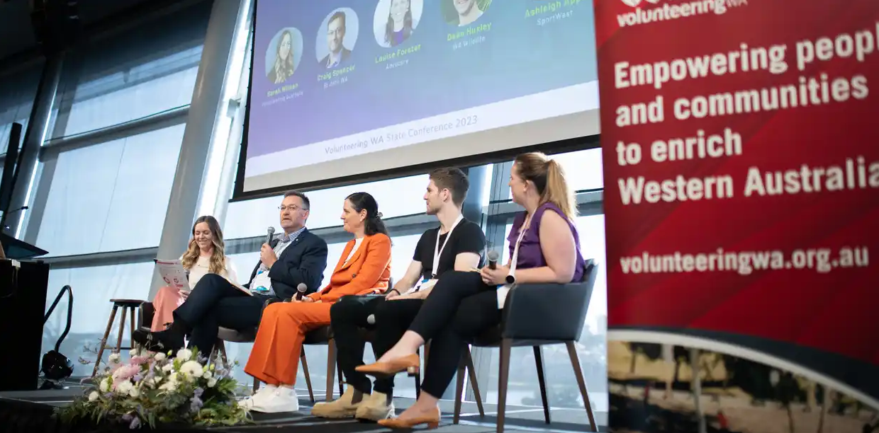 people sitting on stage at a conference