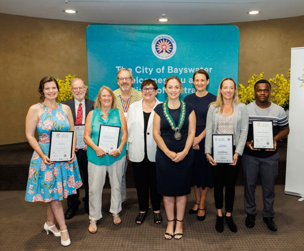 people standing and smiling to camera, some are holding certificates