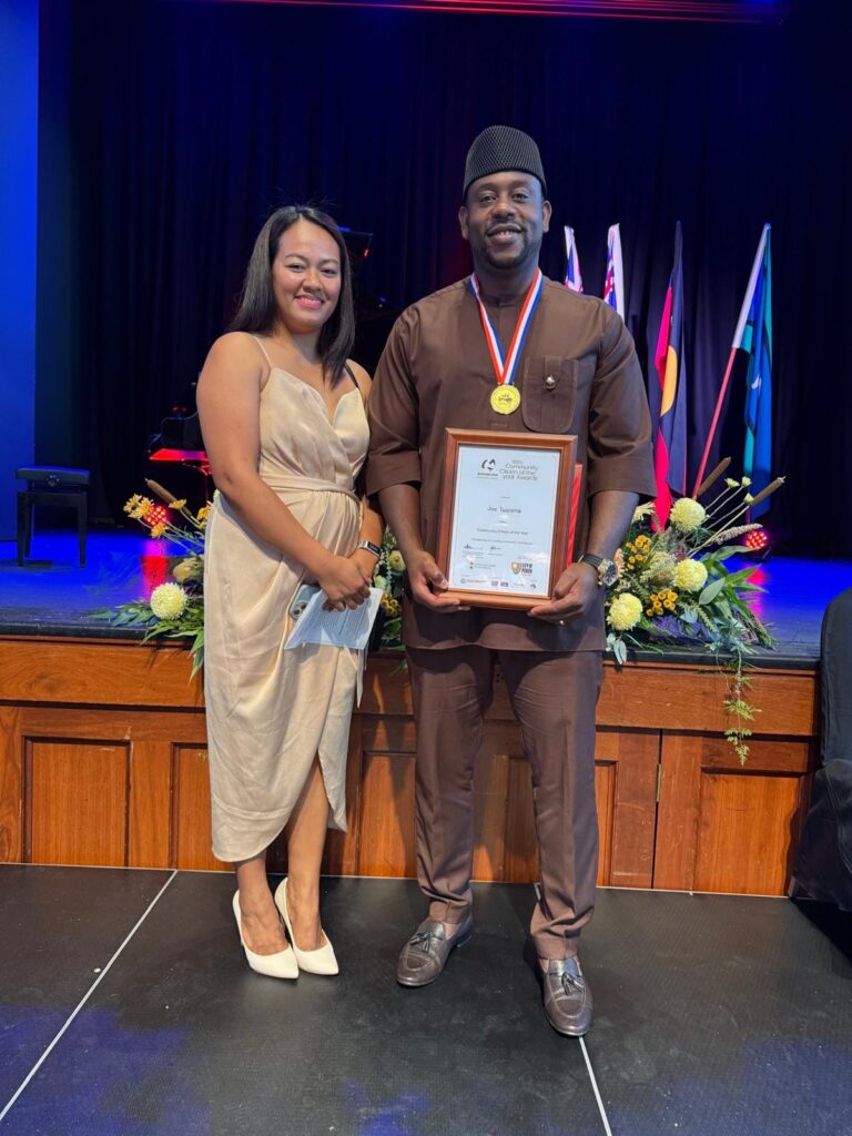 Joe Tuazama smiling to camera and holding a certificate with woman next to him