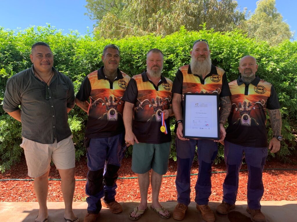 five men smiling to camera with a certificate and medal, four men wearing the same club t-shirt