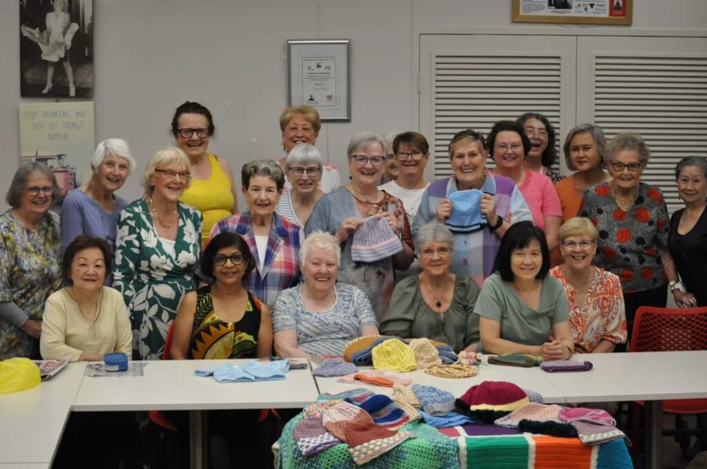 group of seniors smiling to camera and holding crochet items