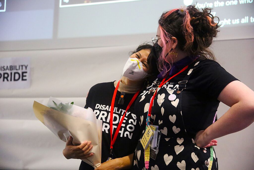 Isabella Choate holding flowers and leaning into another person standing beside them