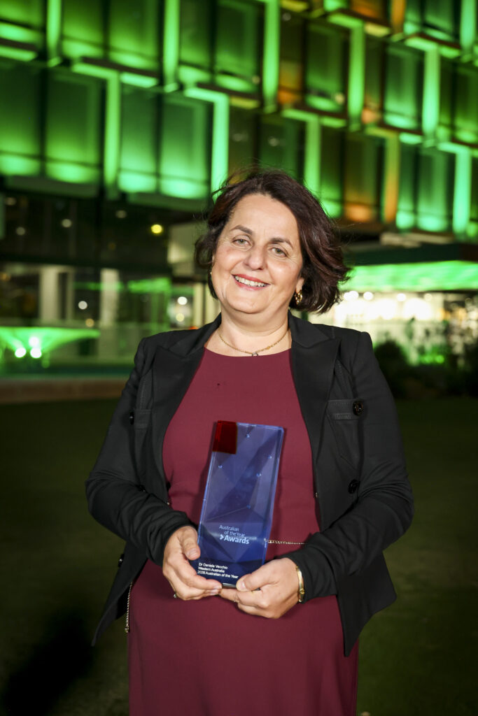 Daniela Vecchio smiles to camera holding trophy