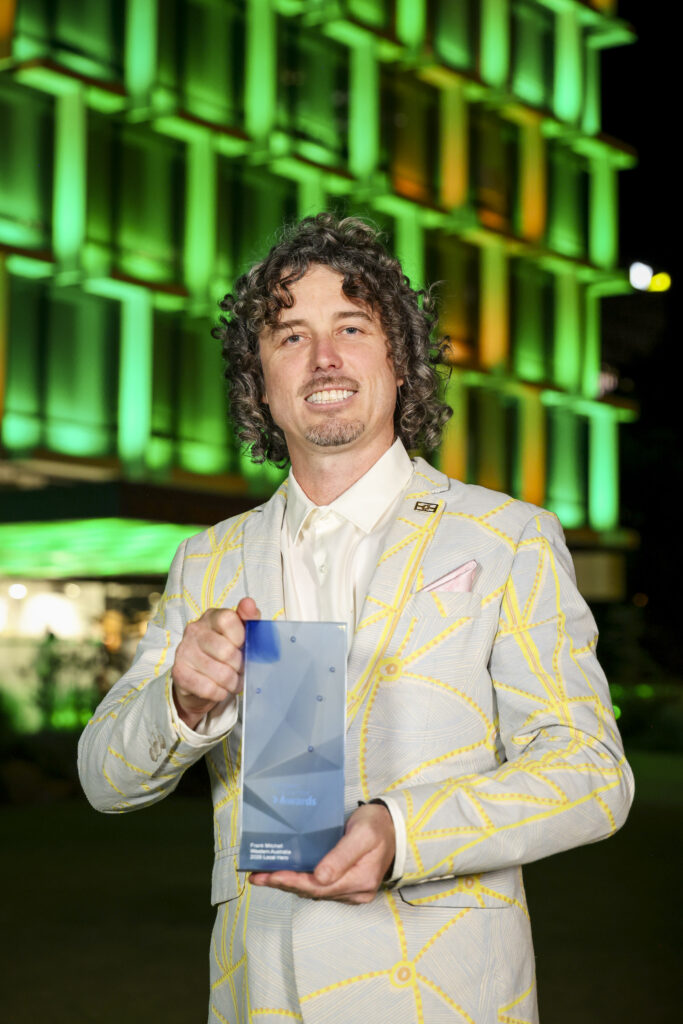 Frank Mitchell smiles to camera holding trophy