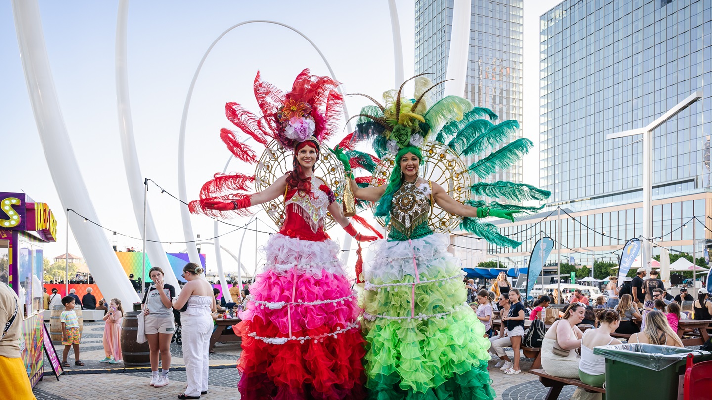 two women on stilts at Elizabeth Quay with people in background