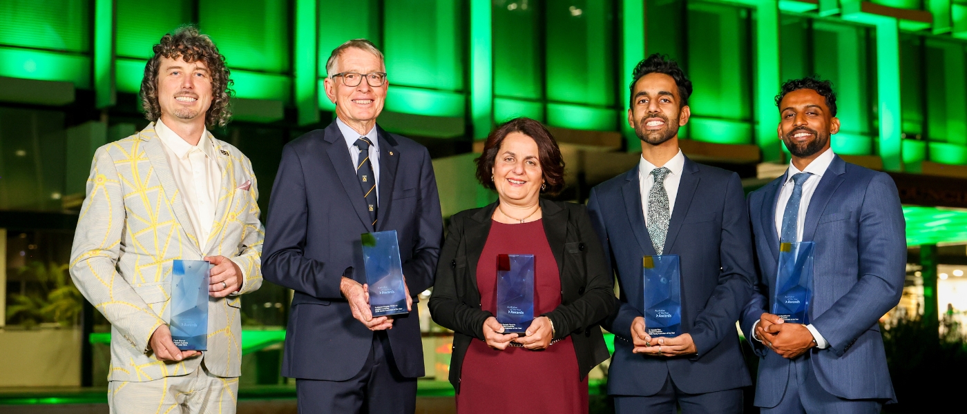 2026 WA Australians of the Year holding trophies in front of green-lit windows