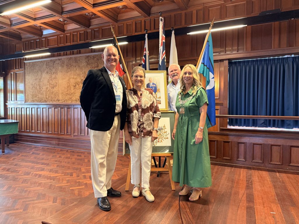 four people standing smiling in front of Australian flags