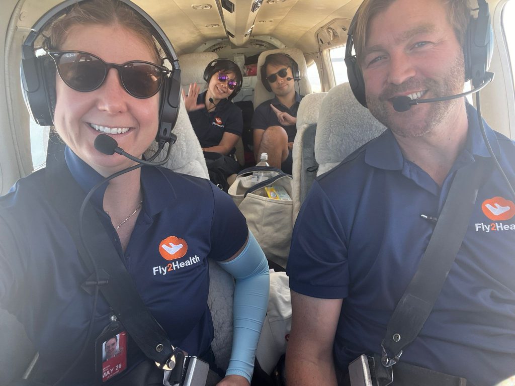 four people sitting in a small plane smiling to camera