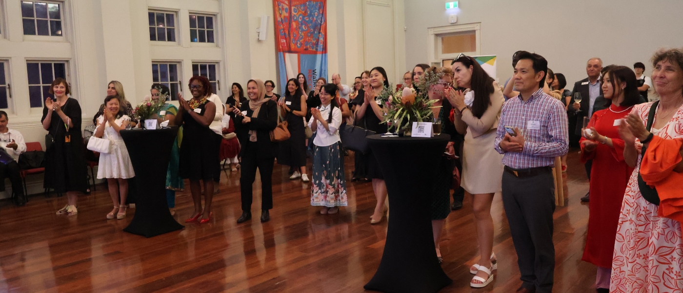 lots of people standing in a hall smiling and clapping