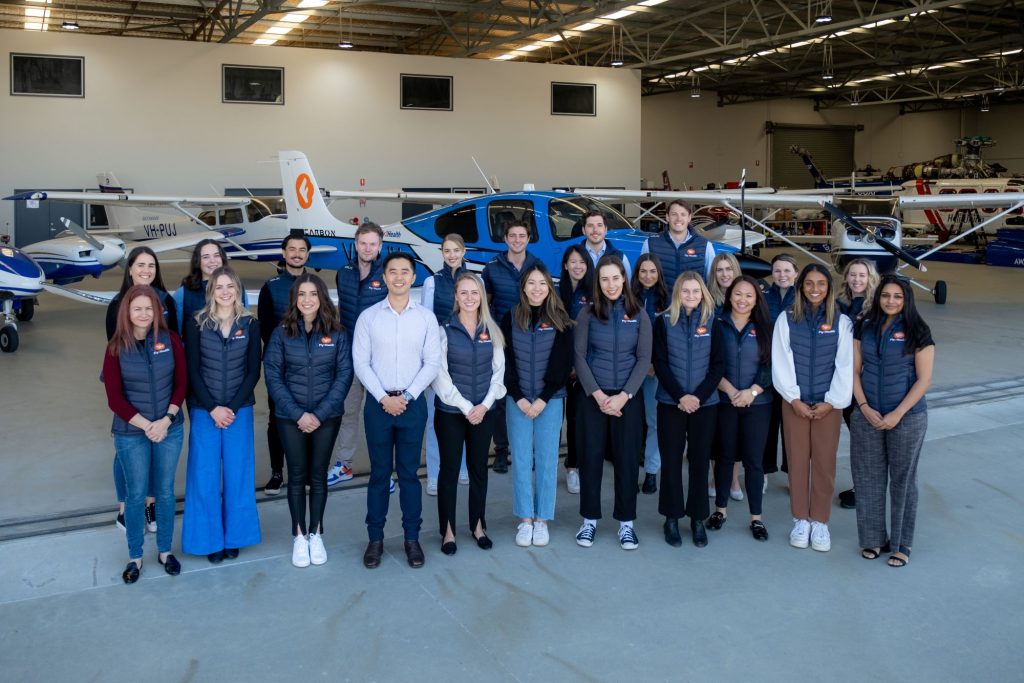 lots of people standing in front of a plane in a plane carrier