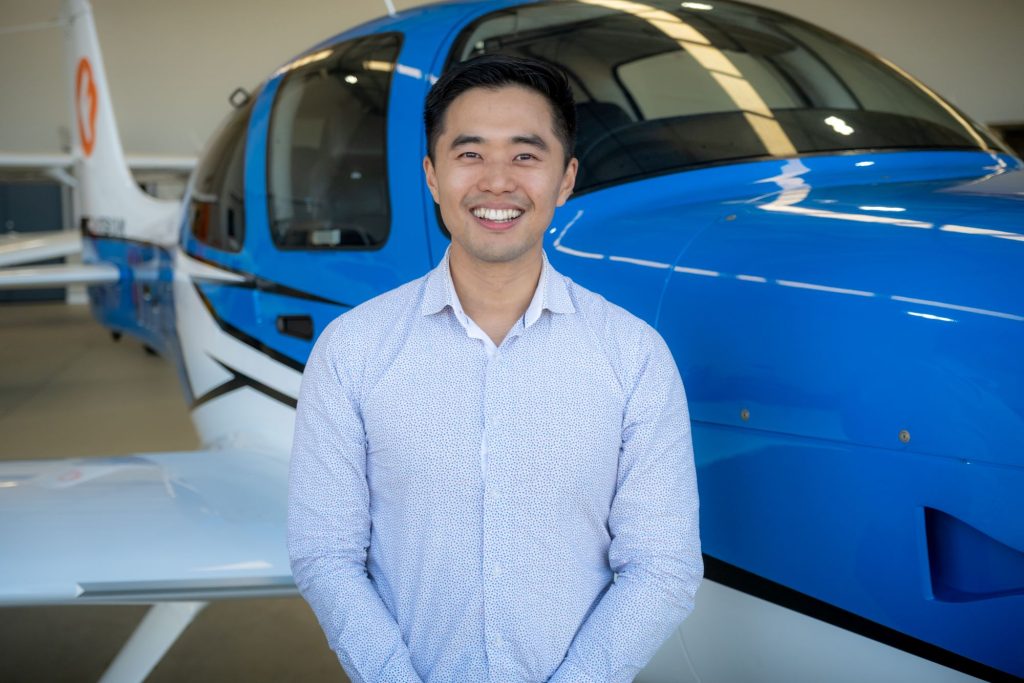 Kennedy Lay smiling to camera and standing in front of plane
