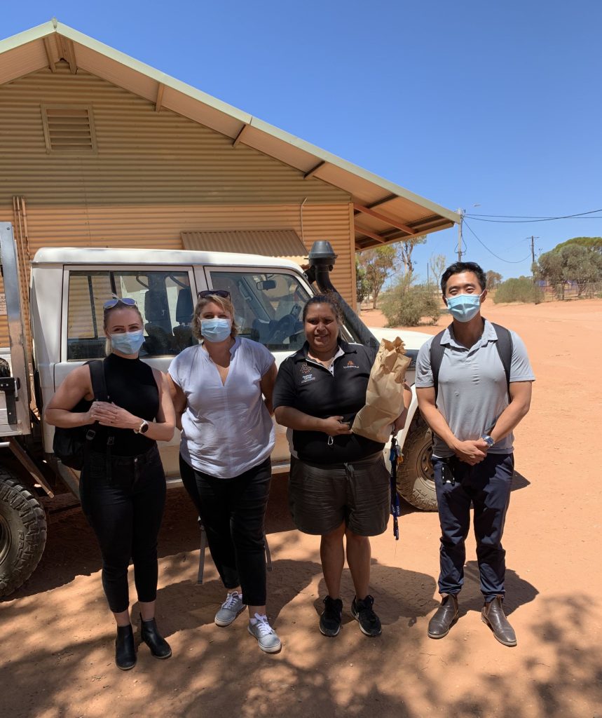 for people standing outside house on sand wearing medical masks