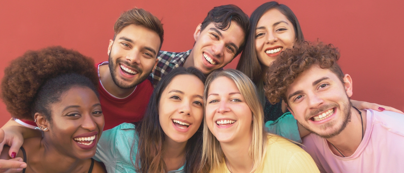 young people smiling to camera in front of red background