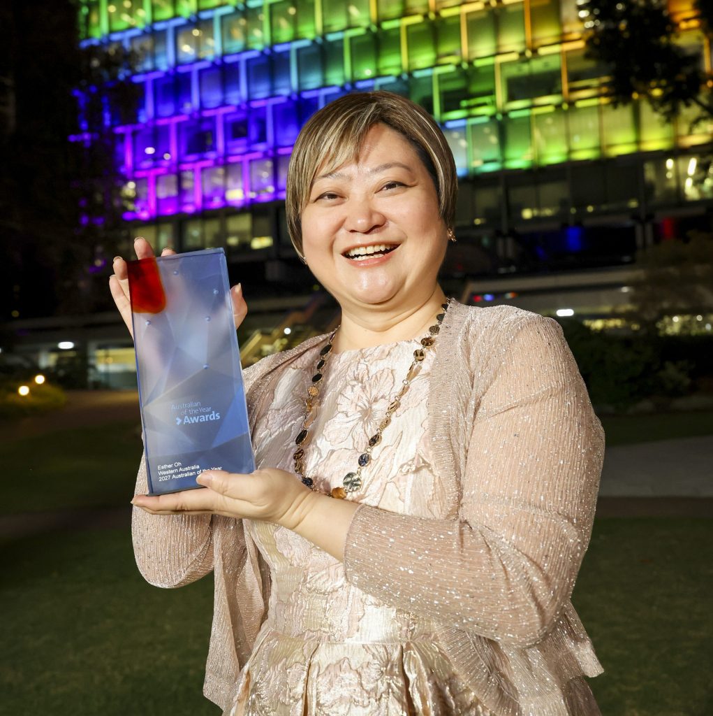 Esther Oh holding award and smiling to camera