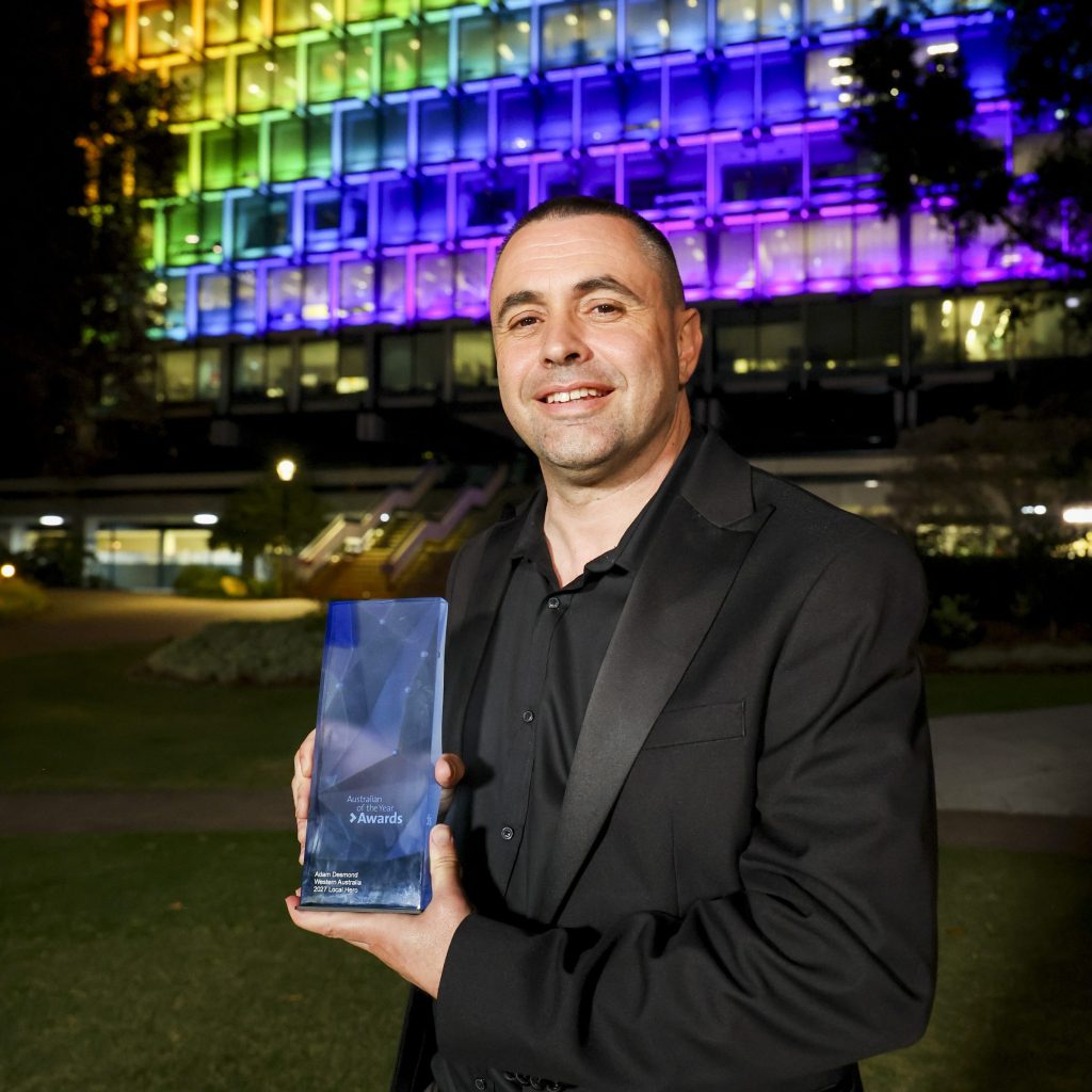 Adam Desmond holding award and smiling to camera